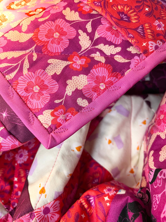 A pretty pink floral quilt with pink vine stitching along the binding. So pretty!