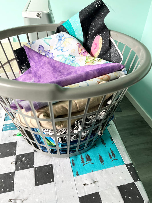 A basket of colourful unfinished quilts sitting on top of an unfinished quilt